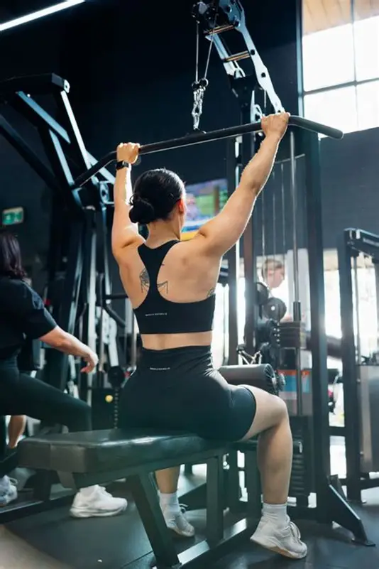 Woman using a pull-up bar machine in a gym